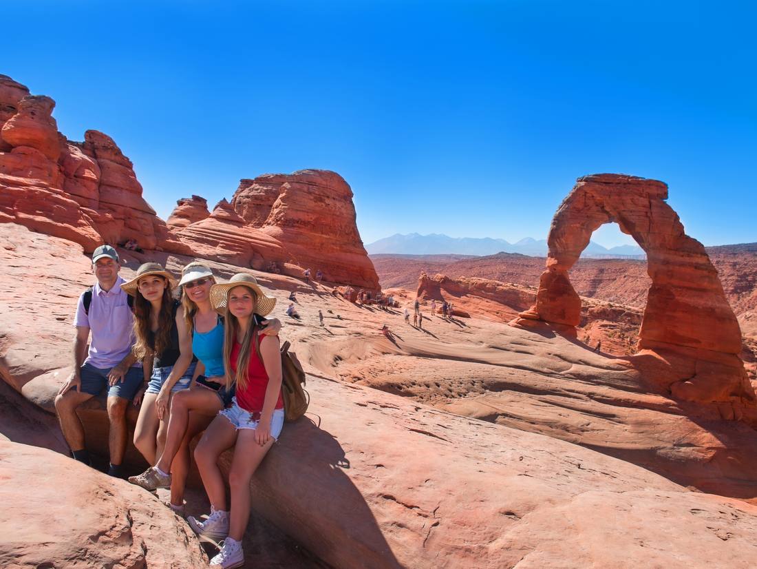 Gezin op de rode rotsen bij Delicate Arch in Arches National Park, Utah, Amerika
