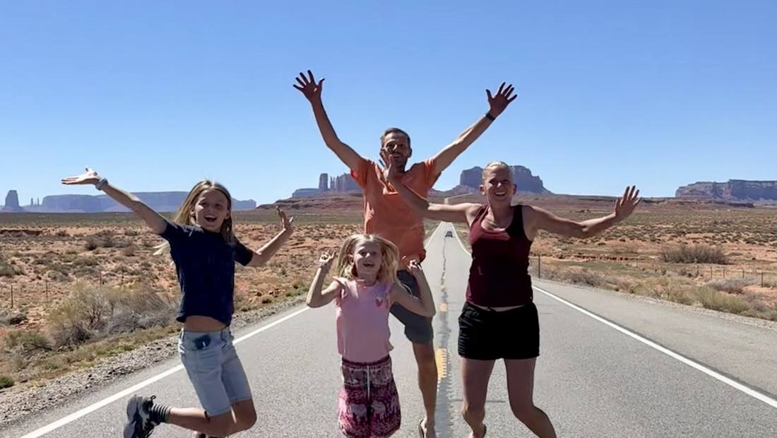 Gezin springt in de lucht op de weg naar Monument Valley, Utah, Amerika