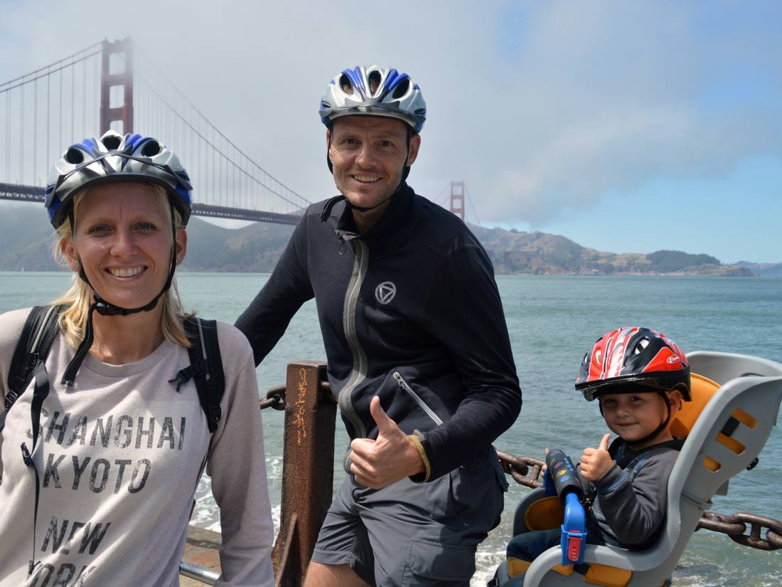 Een gezin op de fiets bij de Golden Gate Bridge, met een kind in het fietsstoeltje, San Francisco, Californië, Amerika