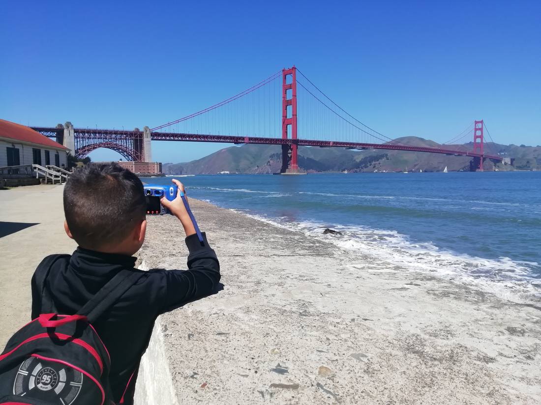 Een jongetje fotografeert de Golden Gate Bridge vanaf het strand, San Francisco, Californië, Amerika