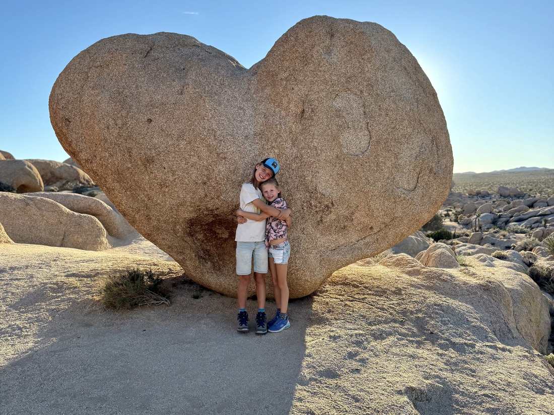 Twee kinderen voor een hartvormige rots in Joshua Tree, Californië, Amerika