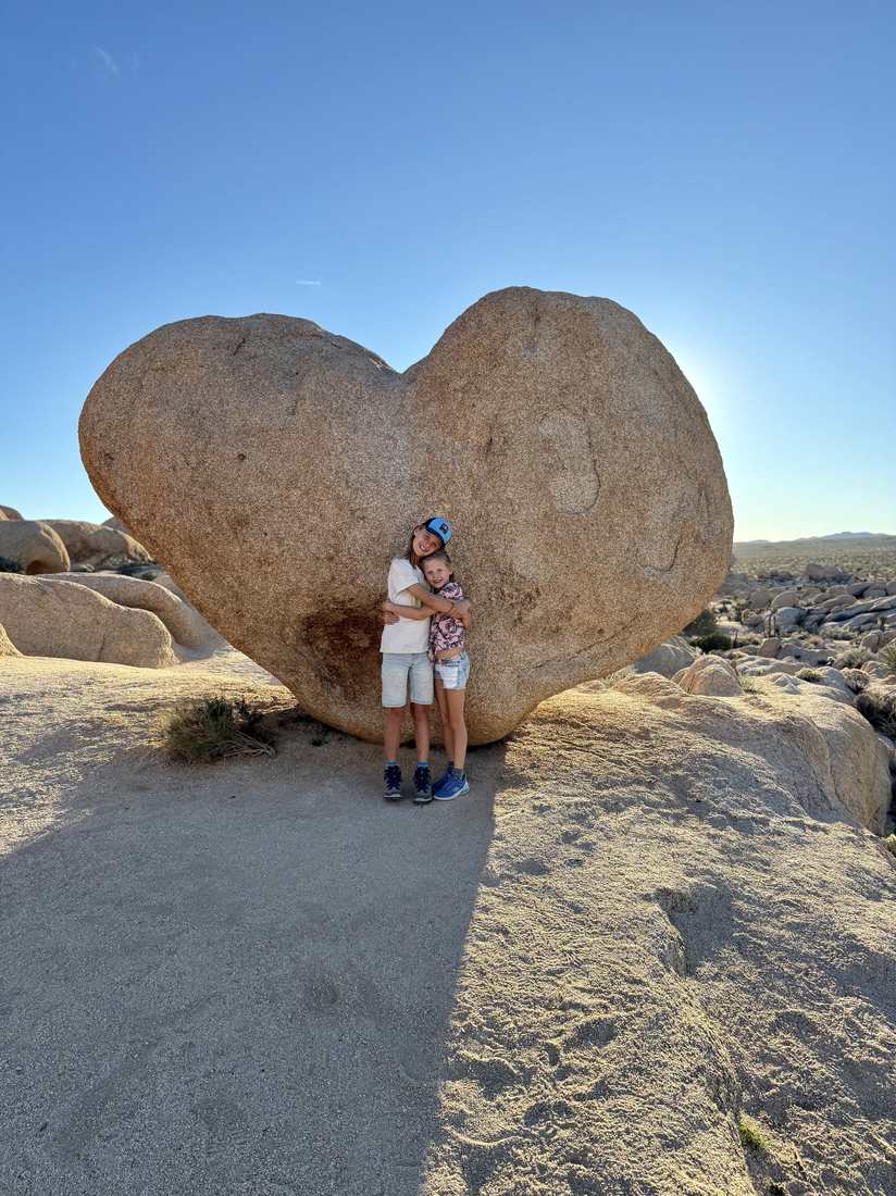 Kind onder een hartvormige rots in Joshua Tree, Californië, Amerika