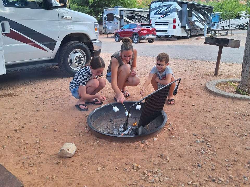 Kinderen bij het vuur op een camping bij Zion, met de campers erachter, Utah, Amerika