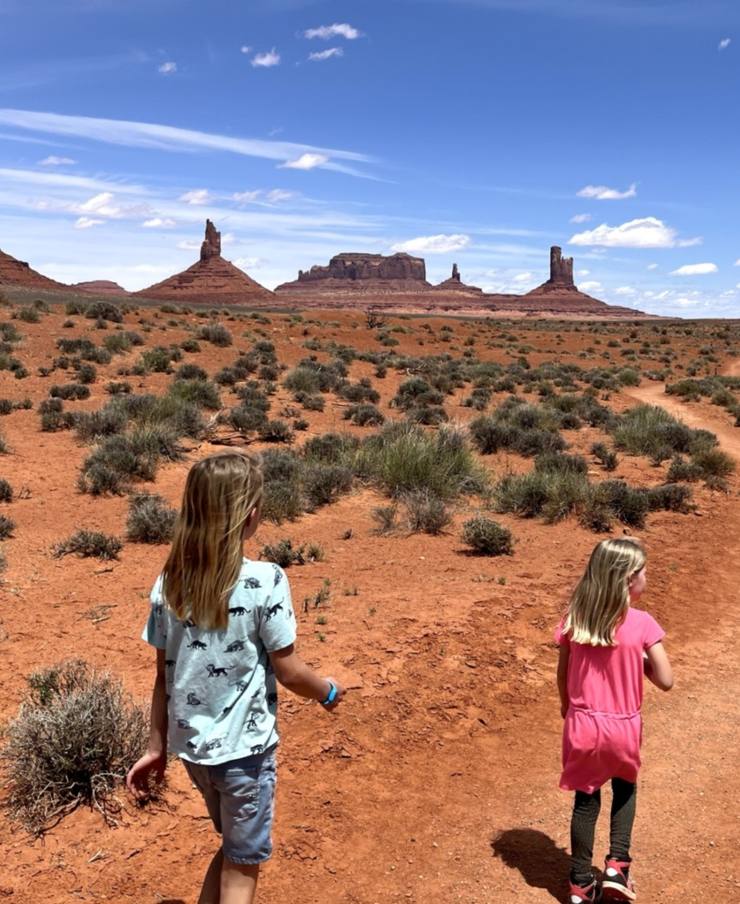 Twee meisjes lopen over het zandpad naar de rotsen van Monument Valley, Utah, Amerika