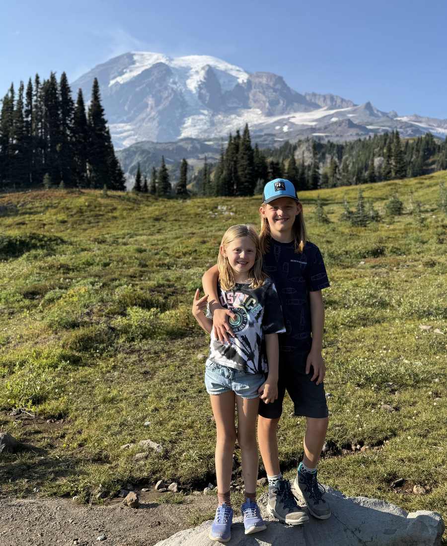 Twee meisjes op een bergweide met Mount Rainier erachter, Washington, het noordwesten van Amerika