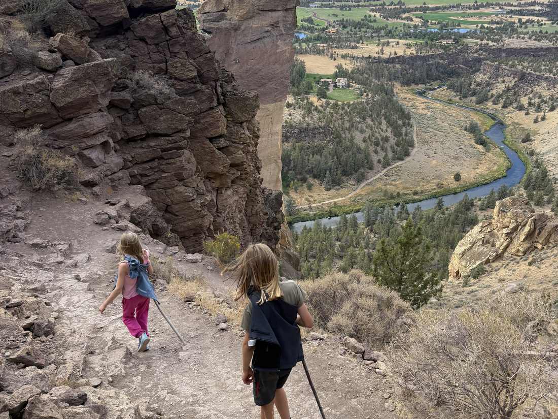 Twee kinderen wandelen op het pad langs de rotsen van Smith Rock bij Bend, Oregon, Amerika
