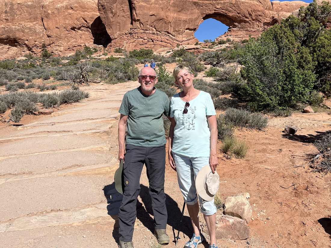 Een ouder stel bij een rotsboog in Arches National Park bij Moab, Utah, Amerika