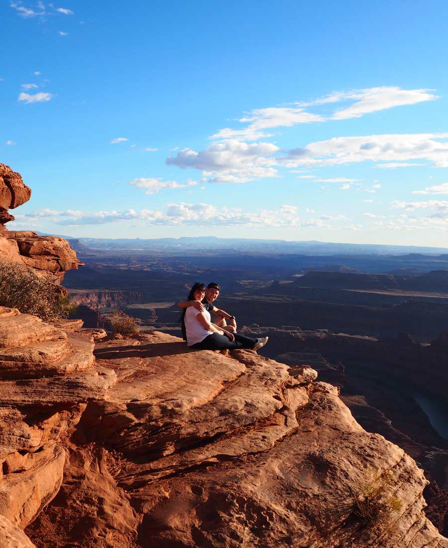 Een stel zit op de rand van de rotsen na een hike, hoog boven de canyons van Utah, Amerika