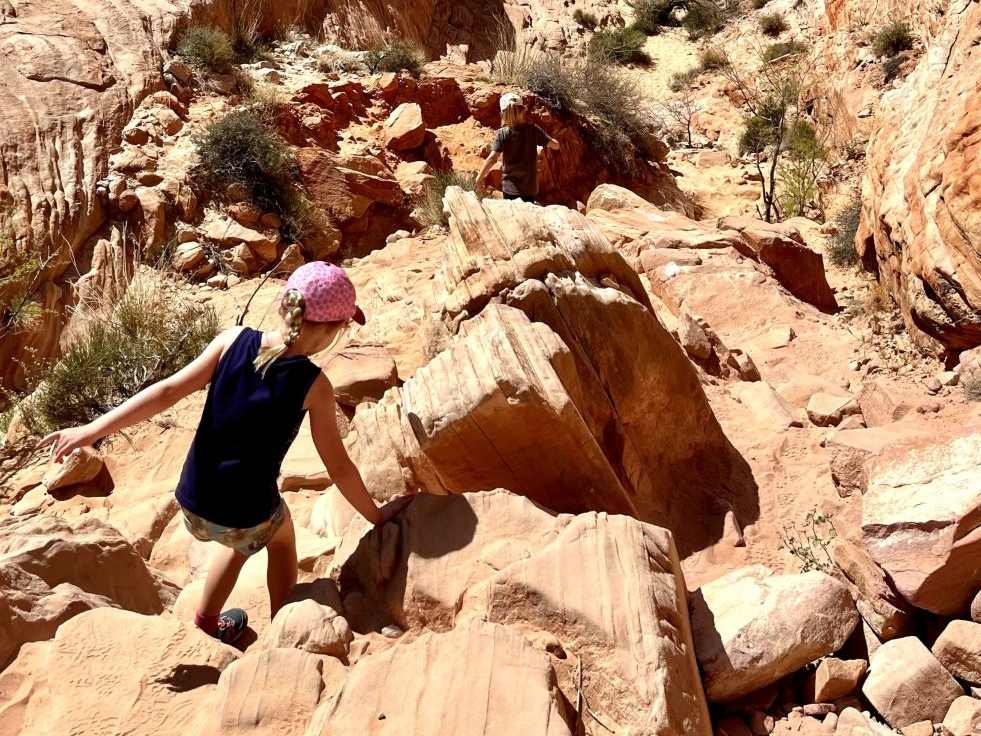 Een meisje klimt over de rode rotsen van Valley of Fire, Nevada, Amerika