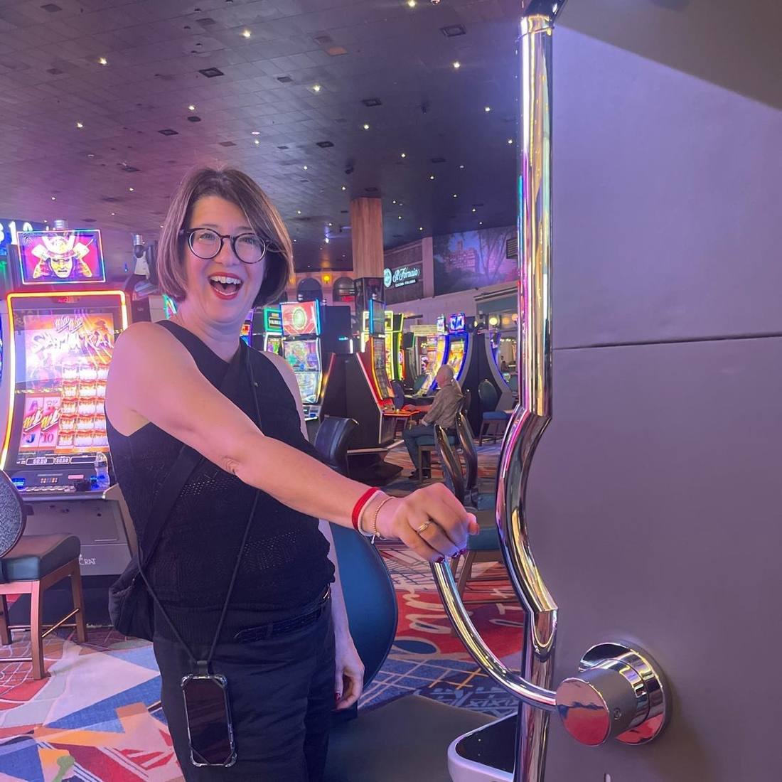 Een reiziger trekt lachend aan de hendel van een gokautomaat in een casino in Las Vegas, Nevada, Amerika
