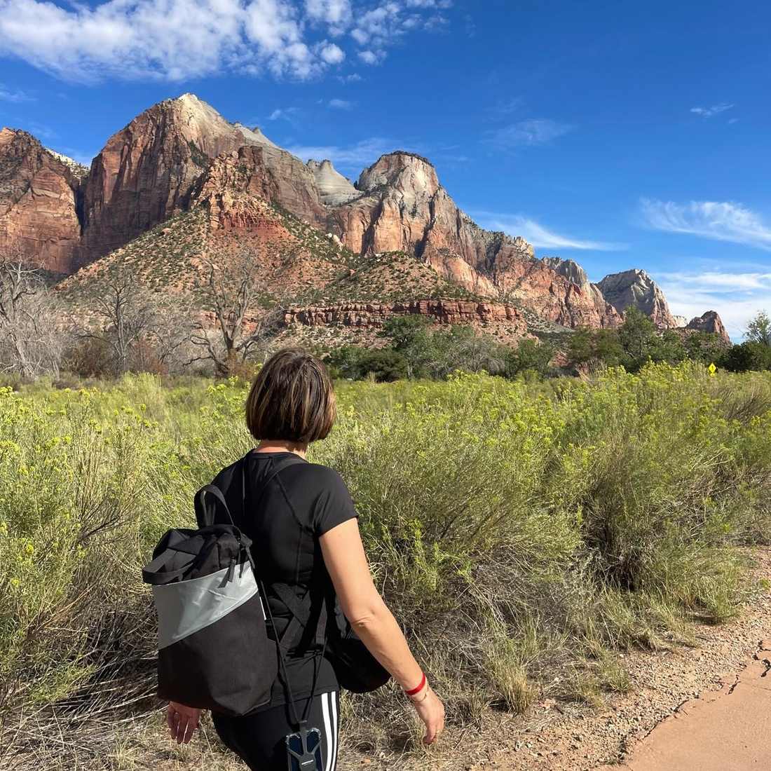 Een vrouw wandelt met de rotsen van Zion voor zich, Utah, Amerika