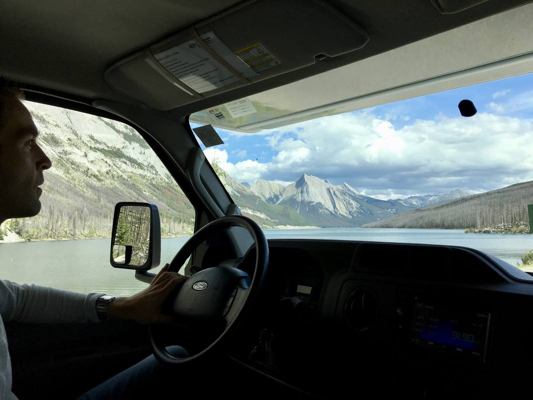 Achter het stuur van de camper, met de bergen door de voorruit, West-Canada