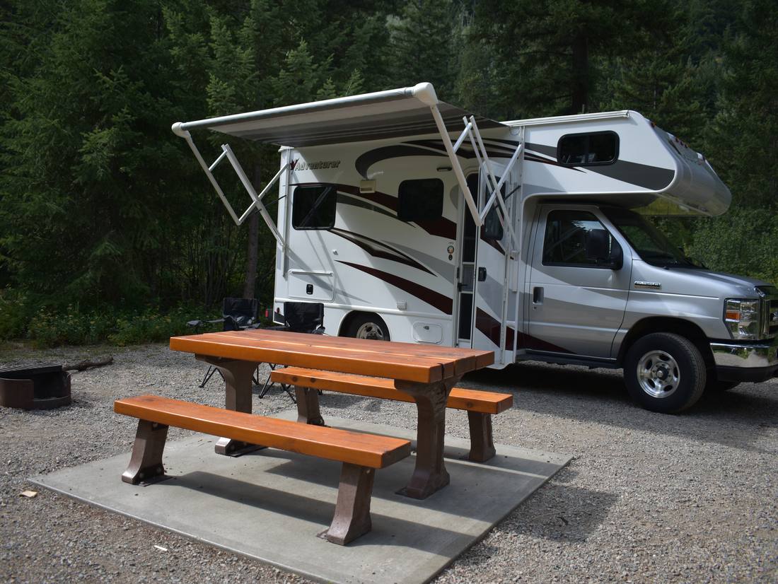 De camper met de luifel uit op een standplaats in het bos, West-Canada