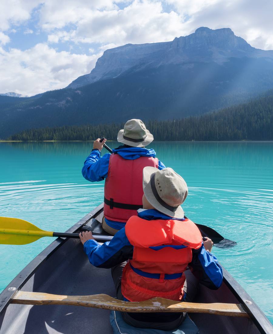 Twee kinderen met zwemvest in een kano op een turquoise bergmeer in de Canadese Rockies, West-Canada
