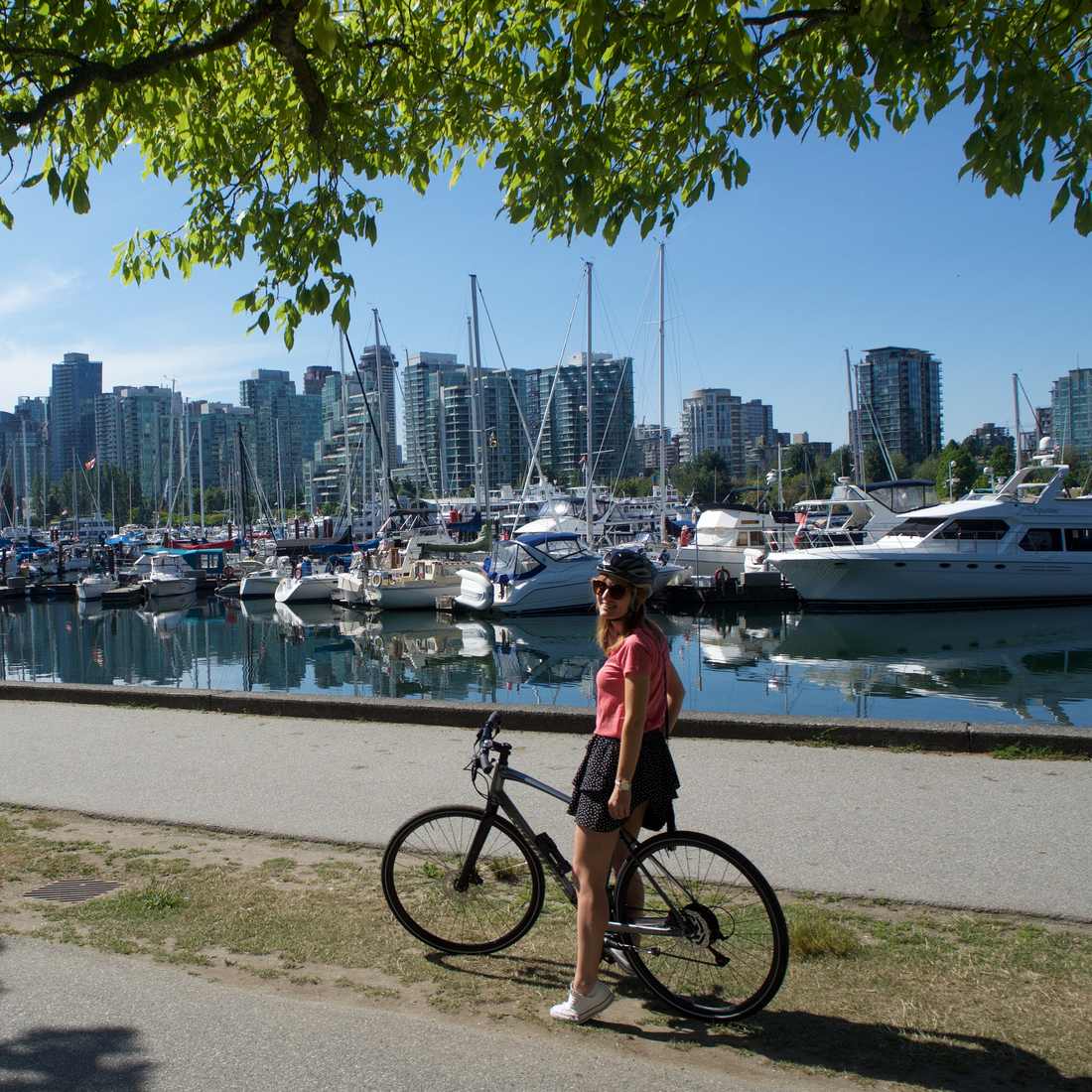 Een fietser op de Seawall langs de jachthaven van Stanley Park, met de skyline van Vancouver, British Columbia, West-Canada