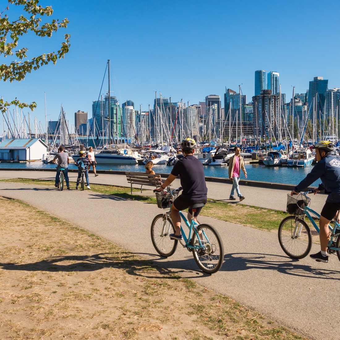 Fietsers over de Seawall langs Stanley Park, met de skyline van Vancouver erachter, British Columbia, West-Canada