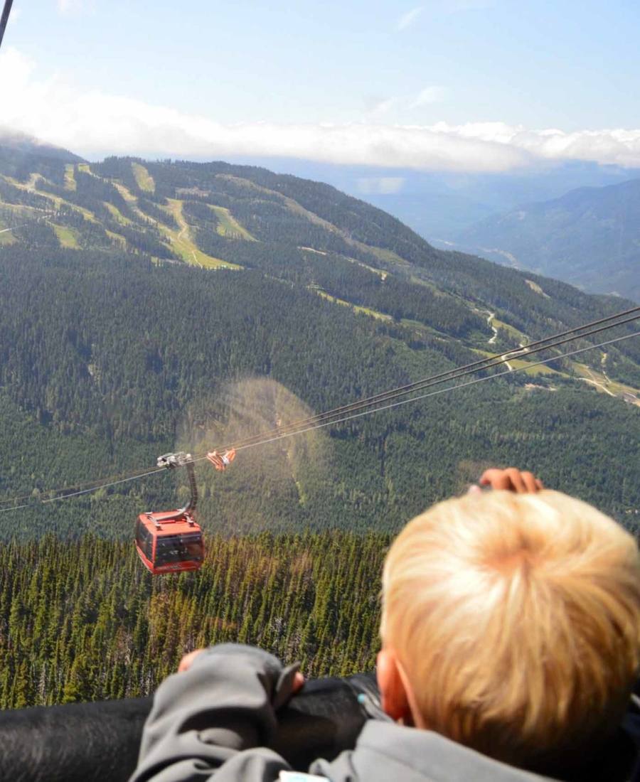 Een kind kijkt vanuit de Peak 2 Peak Gondola uit over de bergen bij Whistler, British Columbia, West-Canada