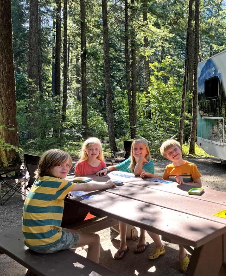 Kinderen aan de picknicktafel naast de camper op een boscamping bij Nairn Falls, British Columbia, West-Canada