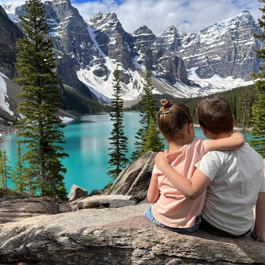 Twee kinderen arm in arm op een rots boven Moraine Lake bij Banff, Alberta, West-Canada