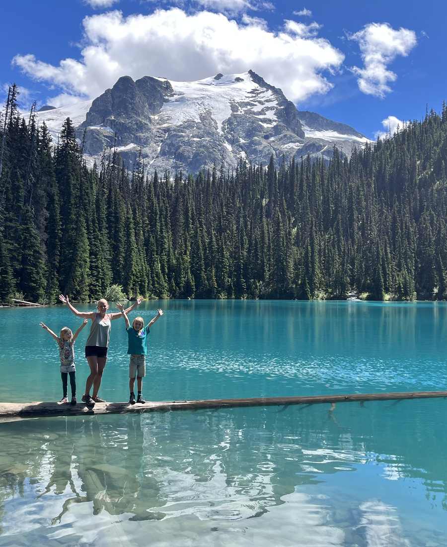 Kinderen op een boomstam in het turquoise water van Joffre Lakes, British Columbia, West-Canada