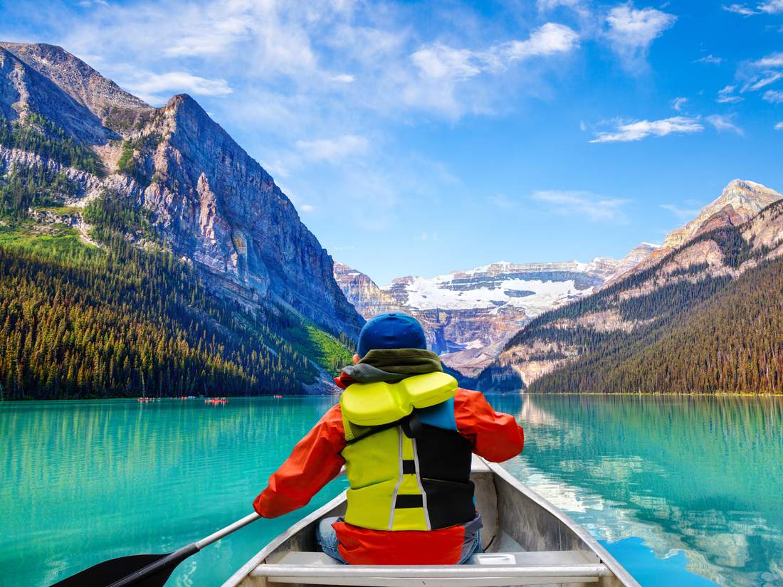 Een kind met zwemvest in een kano op Lake Louise, Alberta, West-Canada