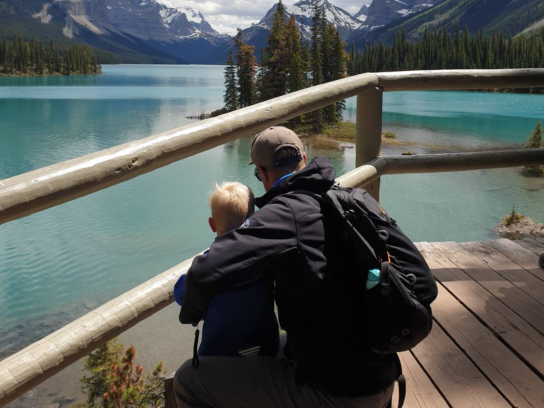 Een opa met zijn kleinkind aan de reling boven Maligne Lake bij Jasper, Alberta, West-Canada