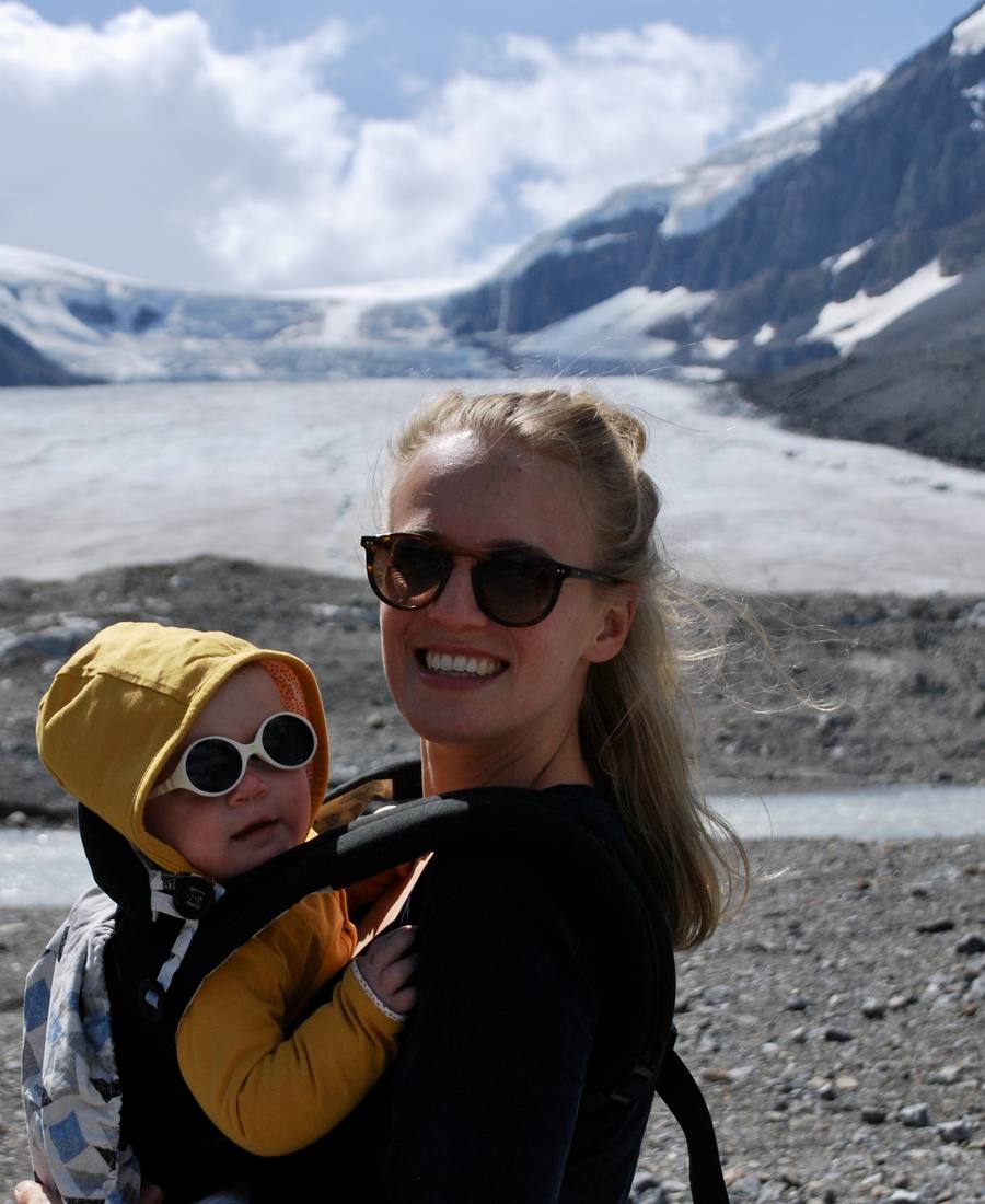 Een moeder met haar peuter in de draagzak voor de Athabasca-gletsjer aan de Icefields Parkway, Alberta, West-Canada