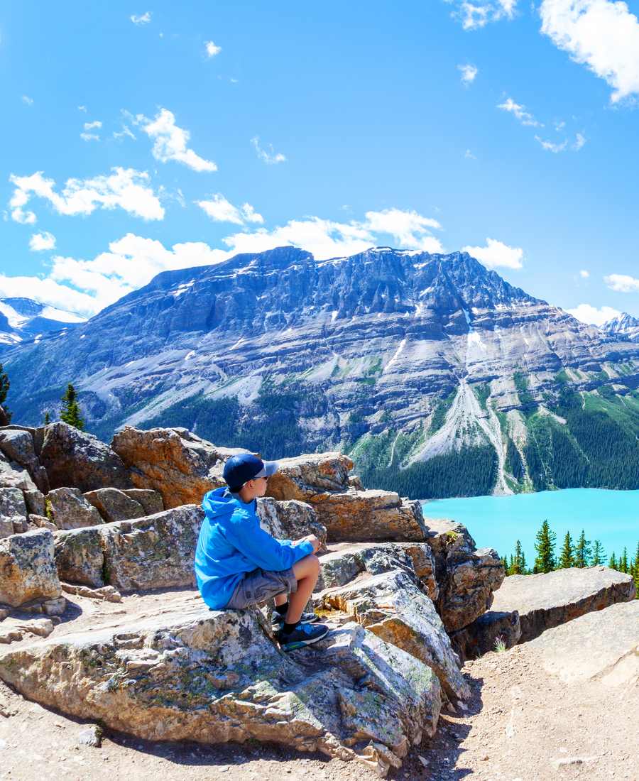 Een kind op een rots boven het turquoise Peyto Lake, Icefields Parkway, Alberta, West-Canada