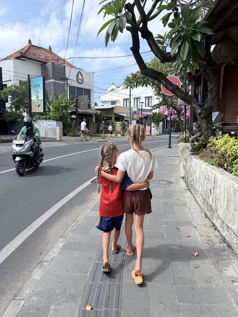 Kinderen lopen over de stoep van een dorpsstraat op Bali, Indonesië