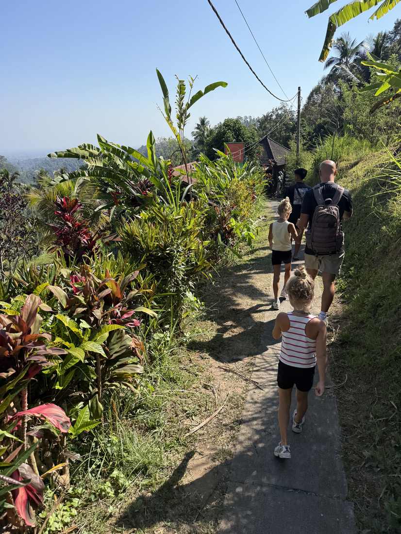 Gezin loopt met rugzakken over een dorpspad op Bali, Indonesië