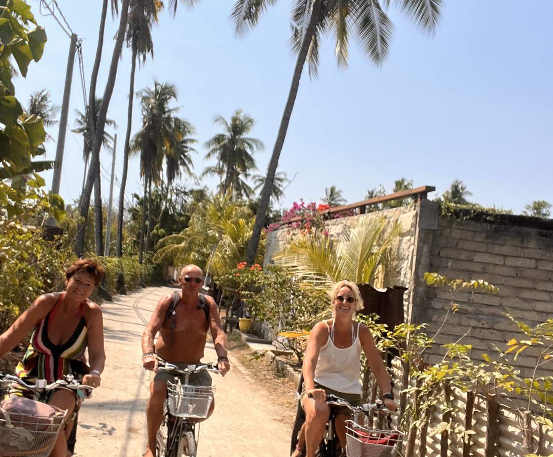 Reizigers fietsen over het zandpad onder de palmen op Gili Air, Indonesië