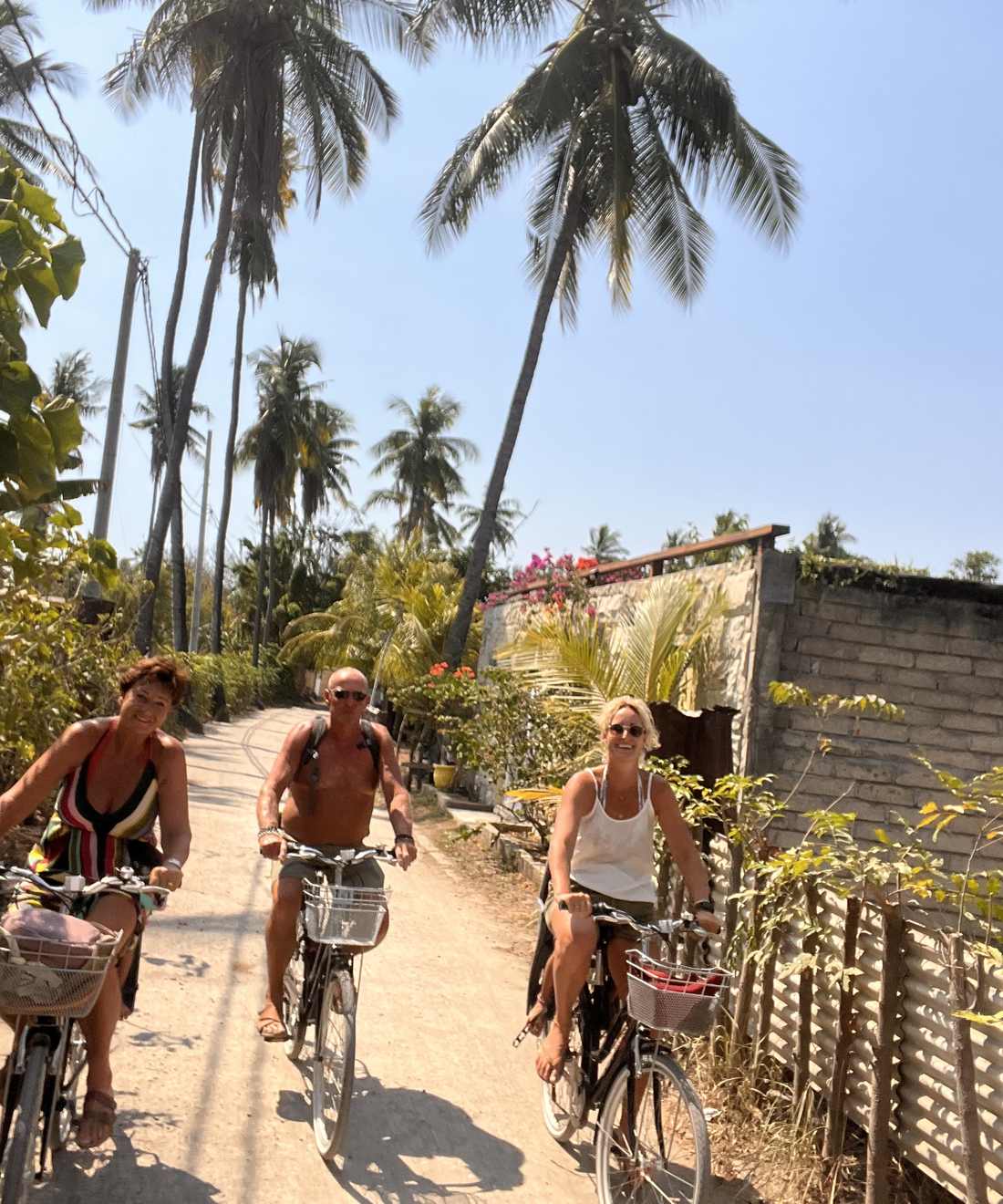 Reizigers fietsen over het zandpad onder de palmen op Gili Air, Indonesië
