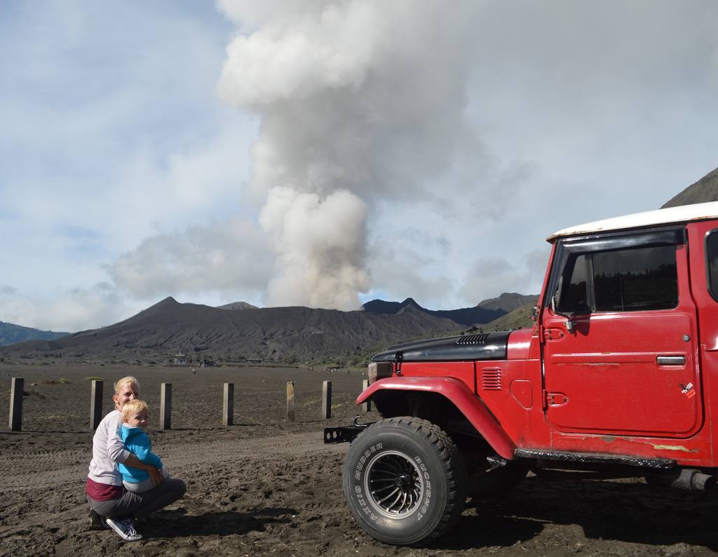 Jeep op de zandvlakte met de rokende Bromo erachter, Oost-Java, Indonesië