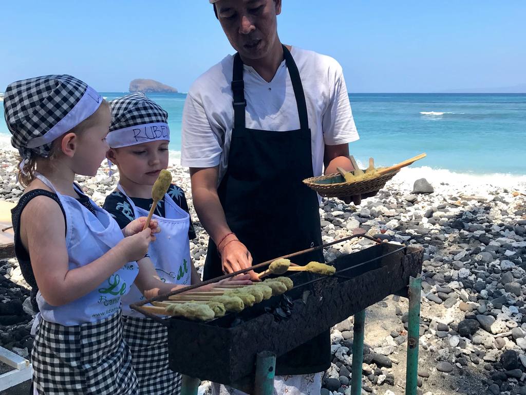 Kinderen koken mee met een kok op het strand van Bali, Indonesië