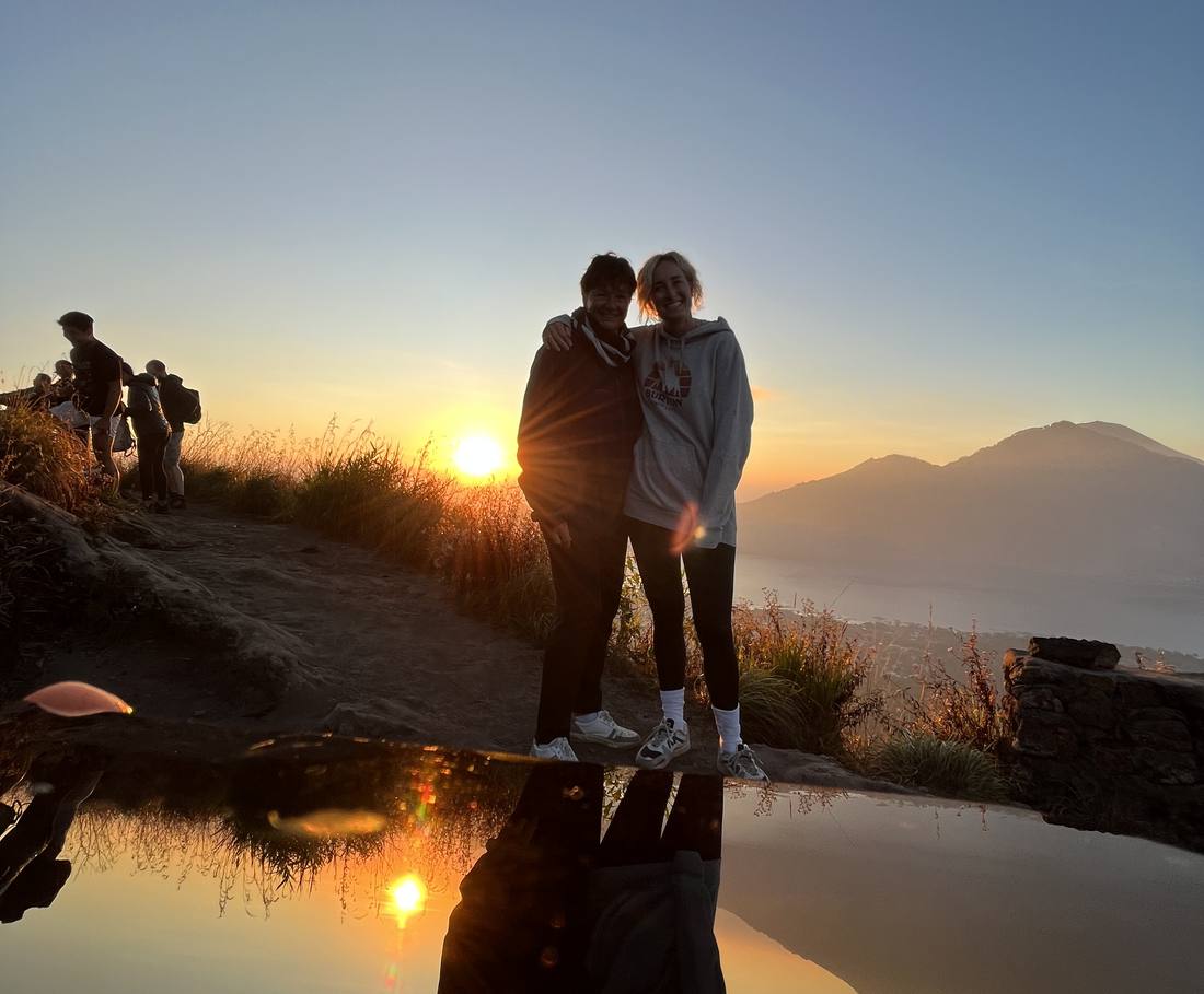 Twee reizigers kijken bij zonsopkomst uit over de vulkaan en het meer, Bali