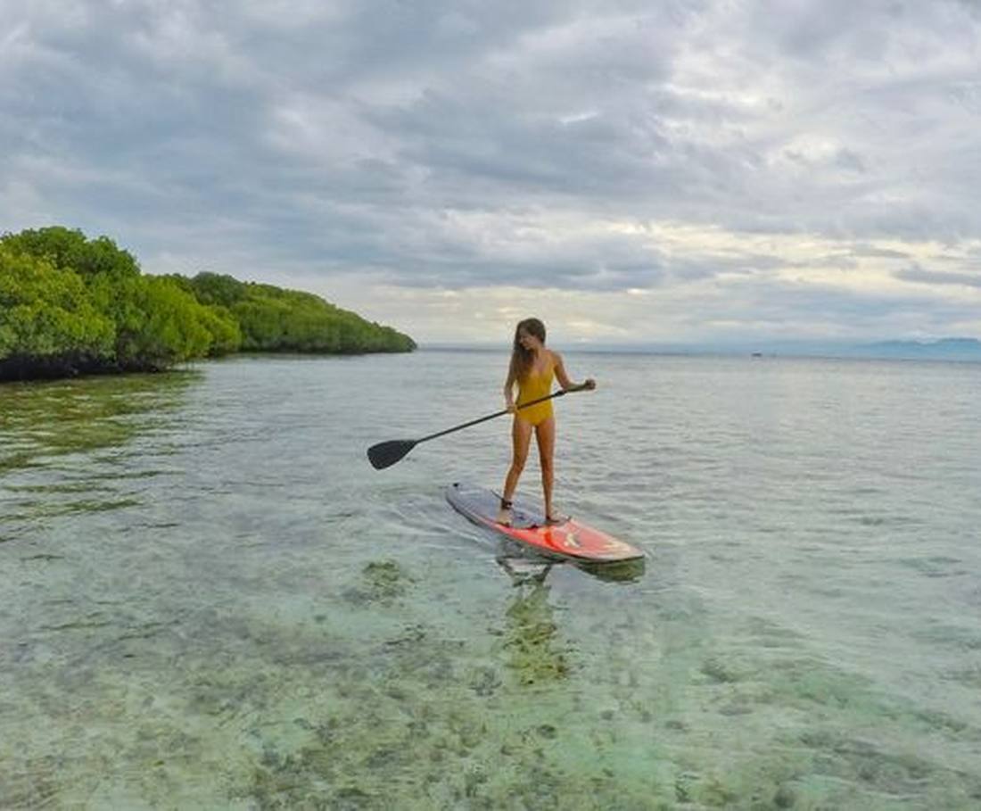 Een reizigster peddelt op een supboard door de mangroves bij Nusa Lembongan, Indonesië