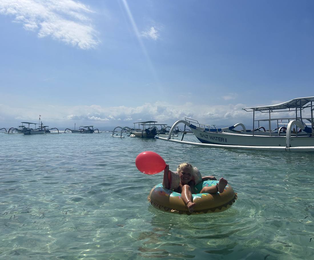 Zwemmen tussen de bootjes voor het strand van Nusa Lembongan, Bali, Indonesië