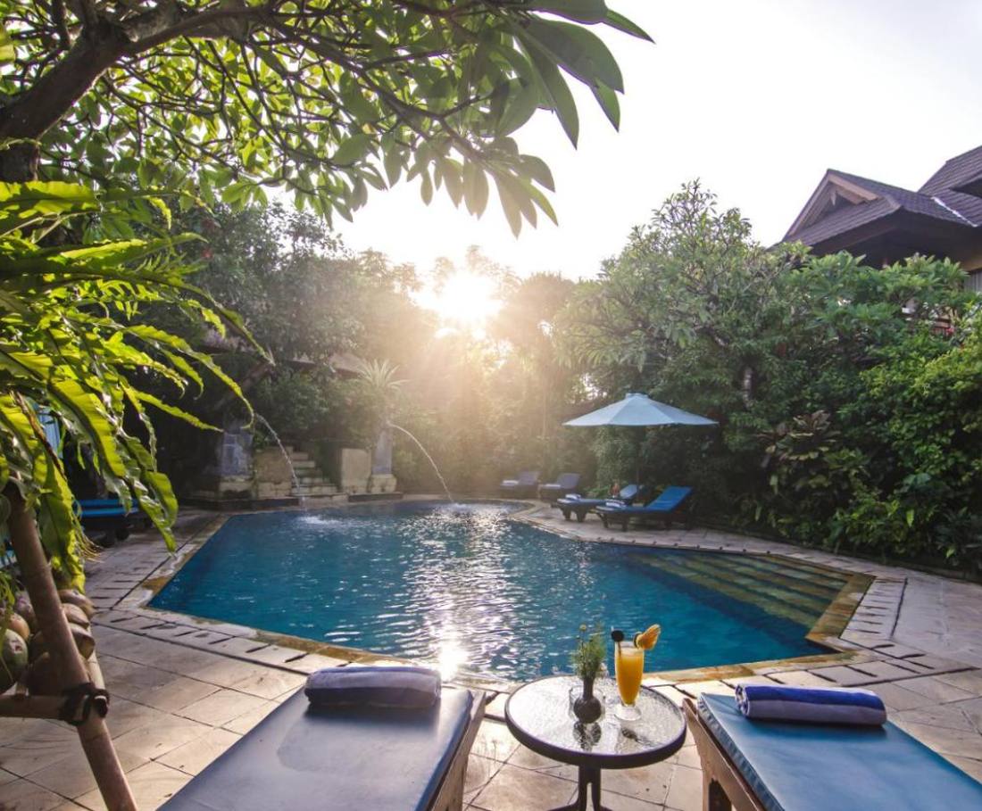 Het zwembad met ligbedden ligt stil in het eerste licht in Sanur, Bali