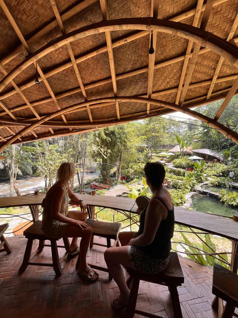 Reizigers aan tafel op een bamboe terras met uitzicht over het groen bij Ubud, Bali, Indonesië