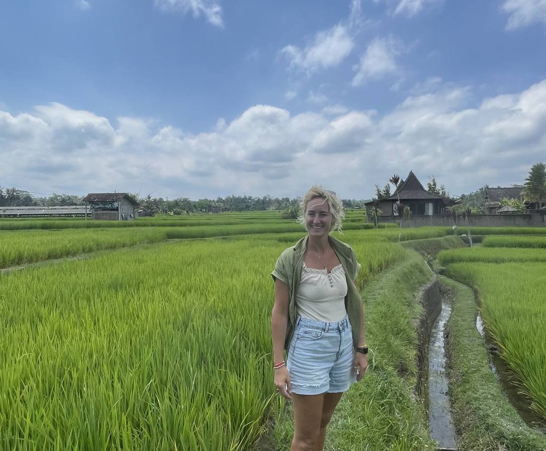 Een reizigster loopt over het pad tussen de knalgroene rijstvelden bij Ubud, Bali