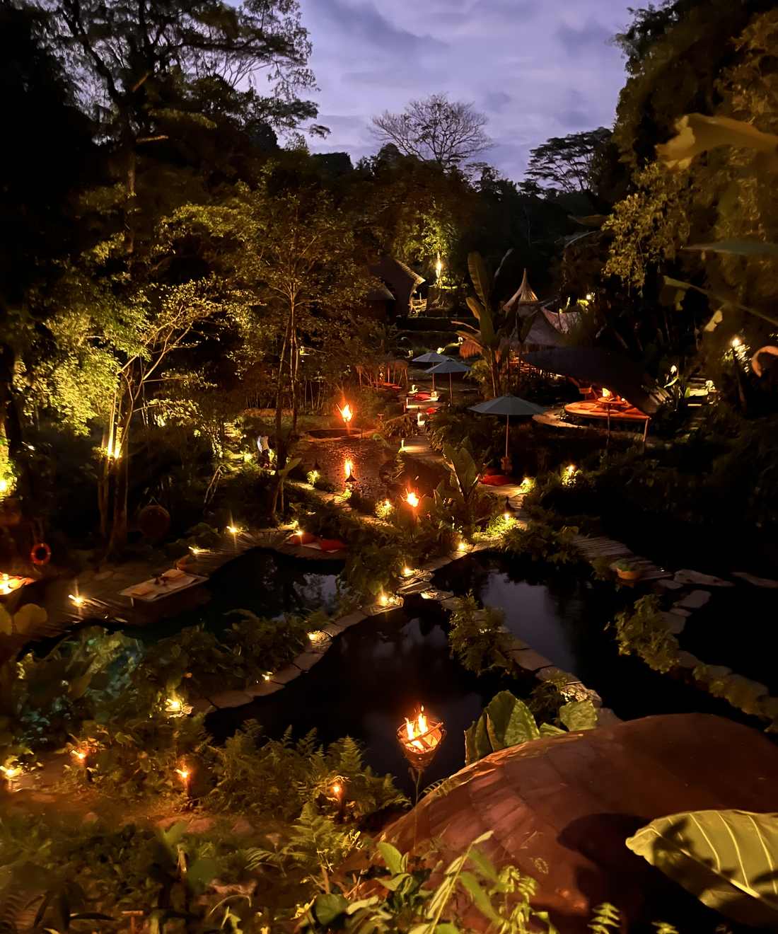 Een restaurant met lichtjes ligt 's avonds verscholen in het groen bij Ubud, Bali