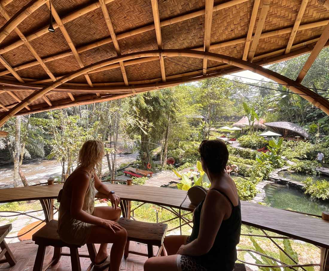 Een stel zit aan tafel op een bamboeveranda met uitzicht over het groen bij Ubud, Bali