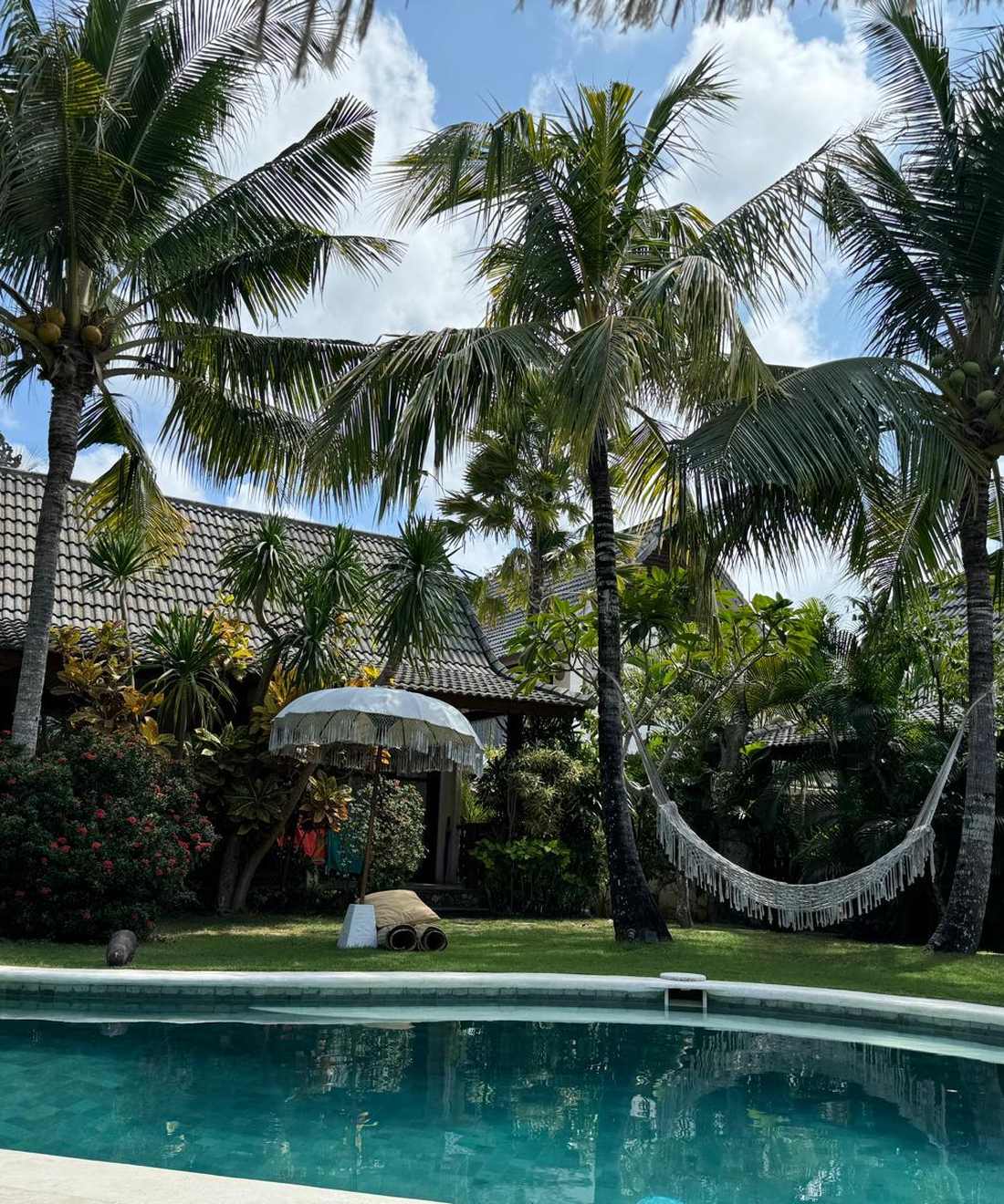 Een hangmat hangt tussen de palmen bij het zwembad in Uluwatu, Bali