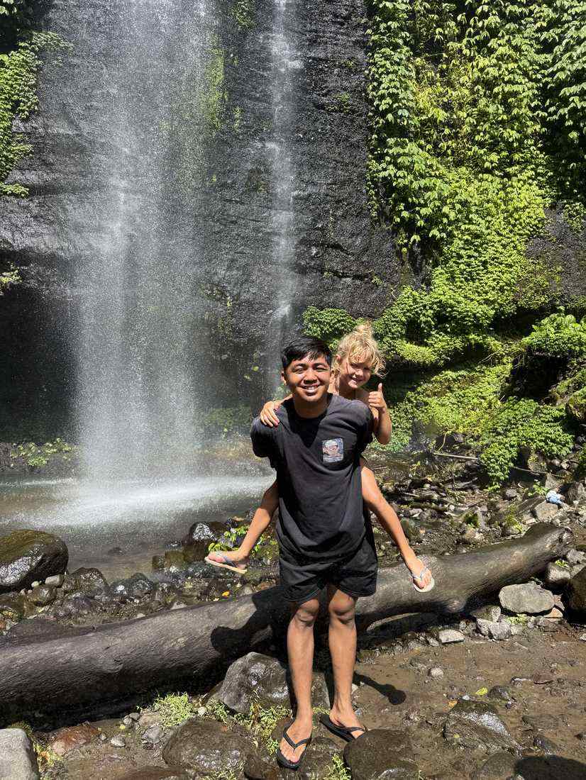 Kind op de schouders van een gids voor een waterval op Bali, Indonesië