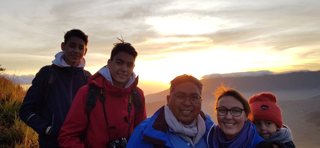 Gezin wacht in dikke jassen op de zonsopkomst boven de vulkaan, Java, Indonesië