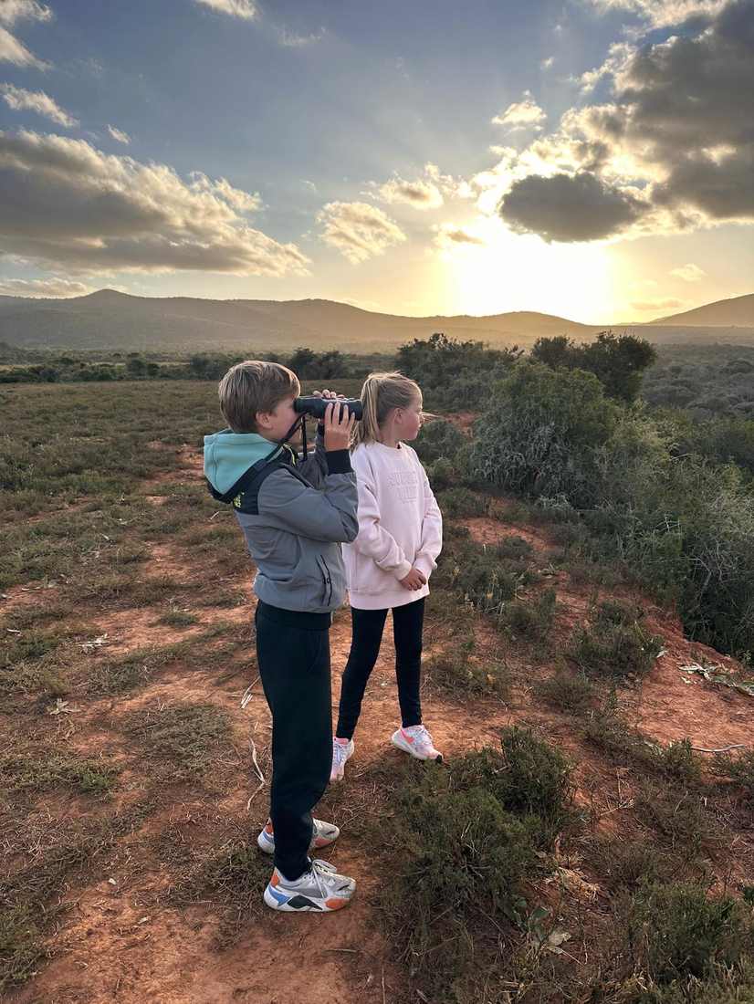 Twee kinderen speuren met verrekijkers bij zonsondergang, Zuid-Afrika