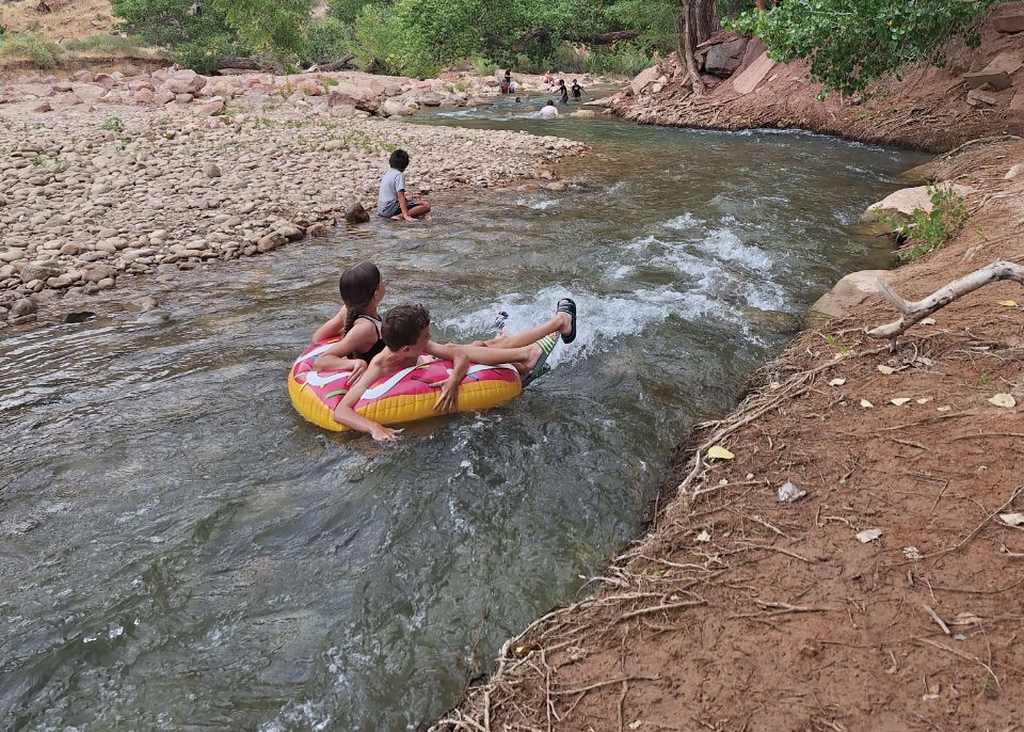 Drijven op een bandje in de rivier tussen de rode wanden van Zion, Utah, Amerika