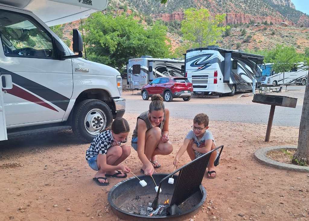De kinderen bij de vuurplaats naast de camper op de camping, Utah, Amerika