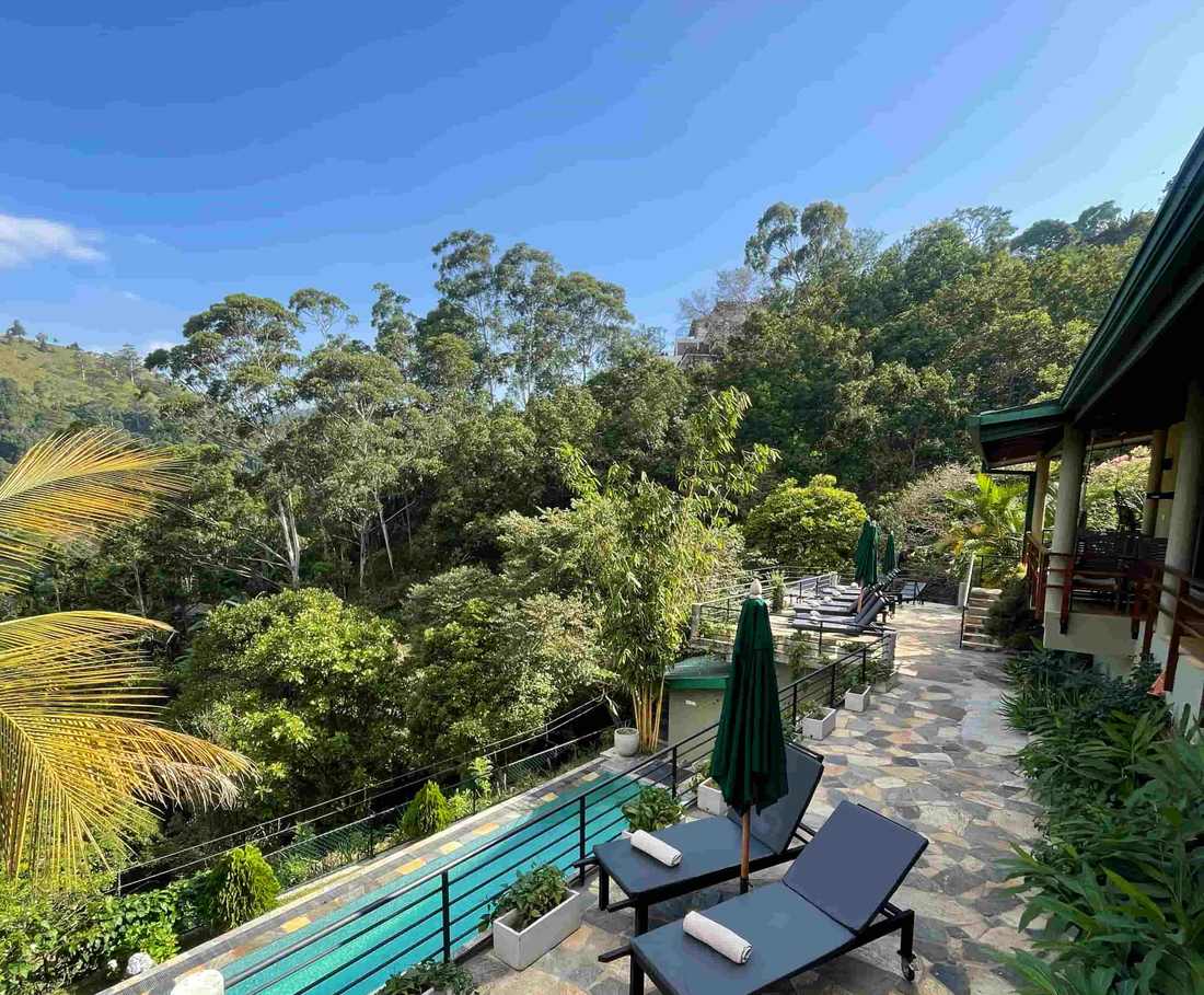 Het terras met zwembad en ligstoelen kijkt uit over het groen bij Ella, Sri Lanka