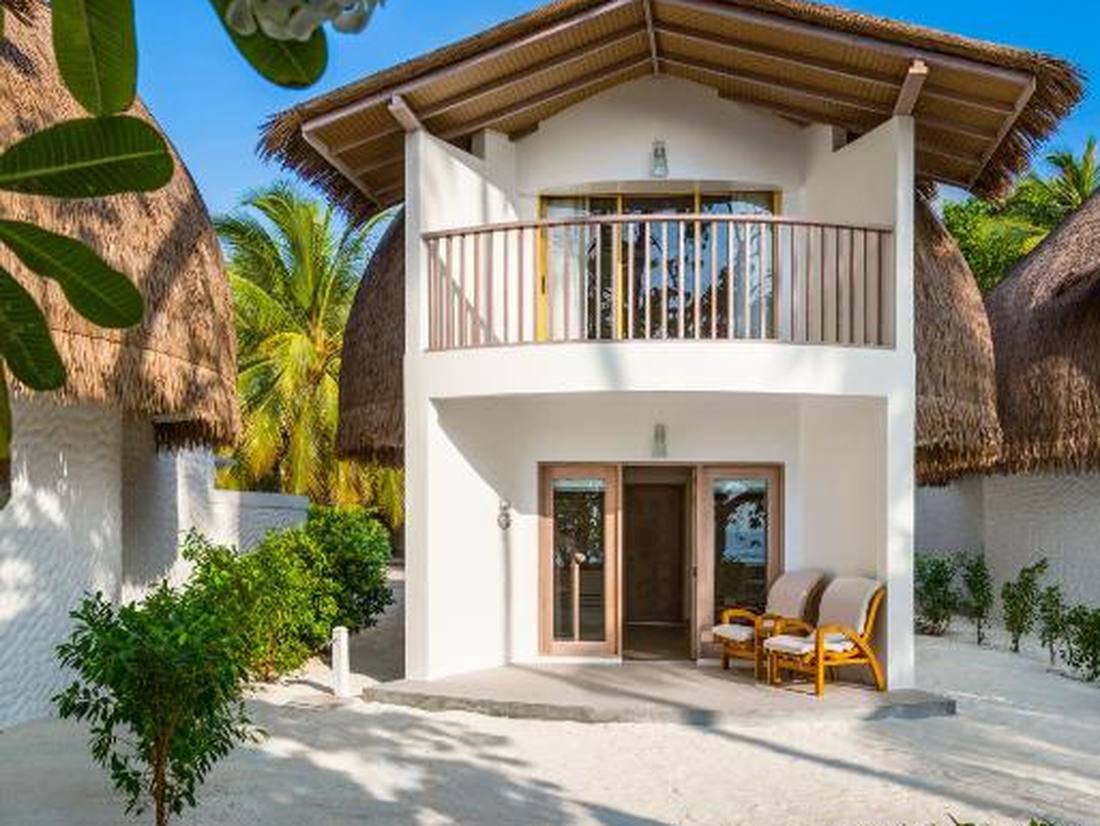 Een villa met rieten dak en een terras op het zand, de Malediven